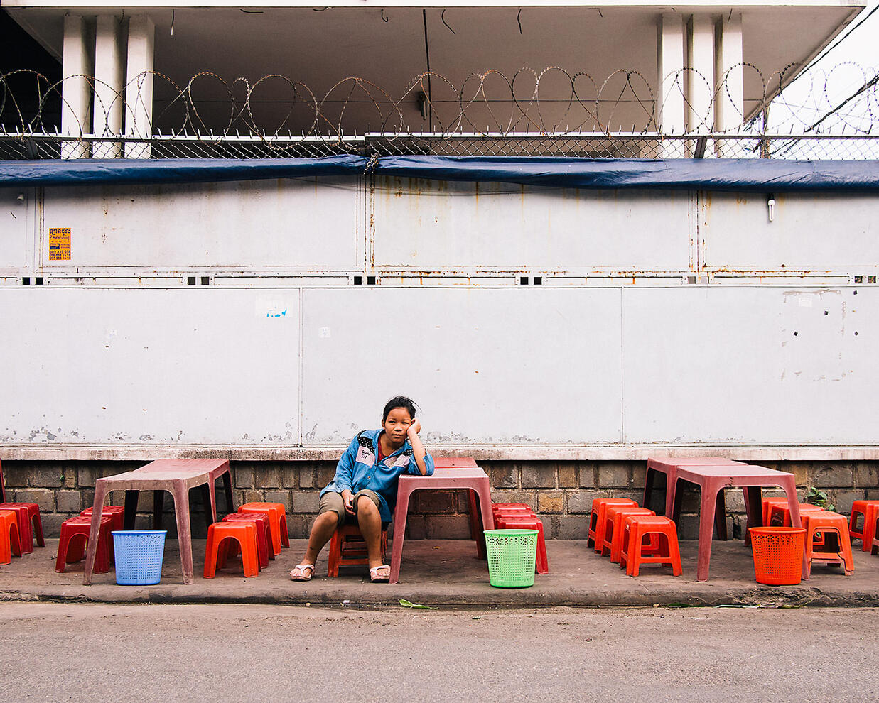 A young girl waits for the customers arrive at her family&#39;s roadside restaurant - Phnom Penh, Cambodia
